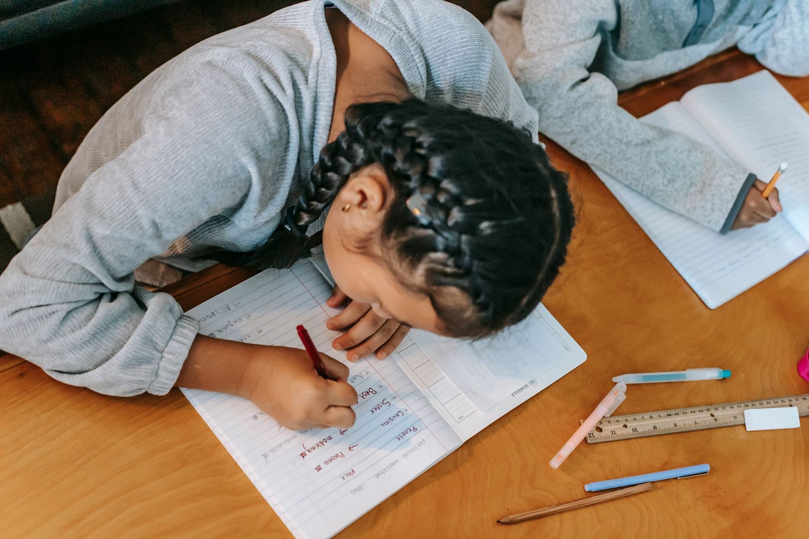 Children writing in their exercise books at a table