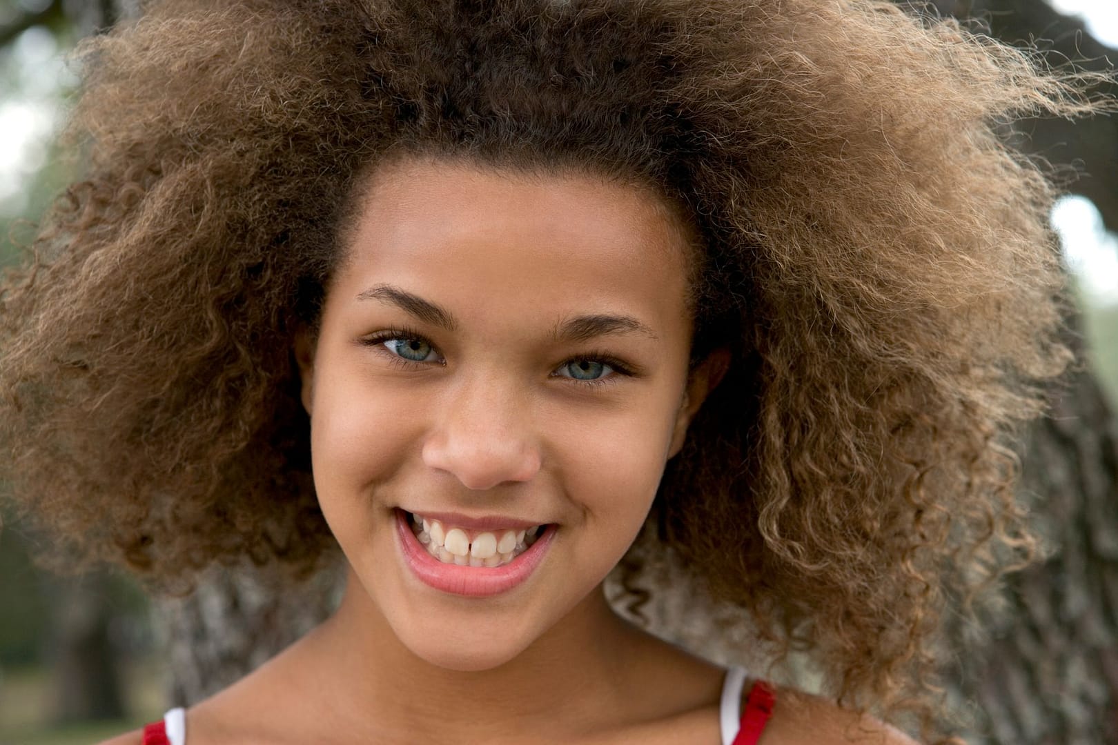Smiling teenager with natural curls outdoors