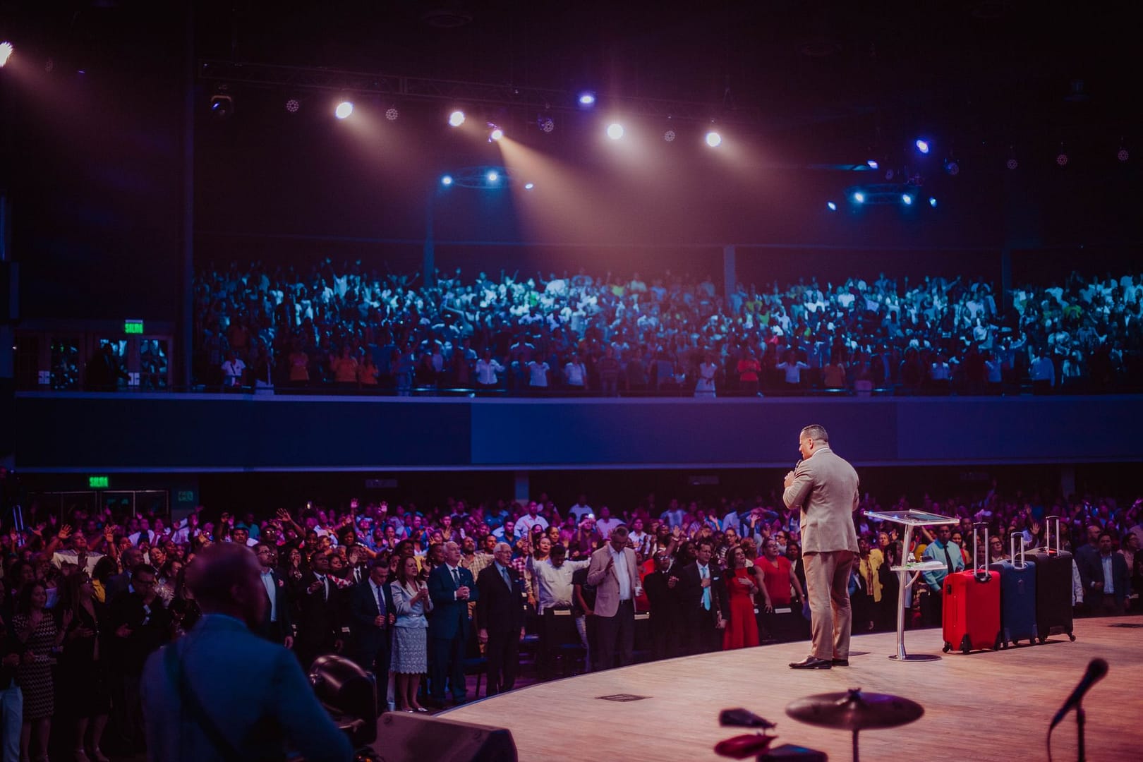 Speaker addressing a large audience on stage at a motivational event