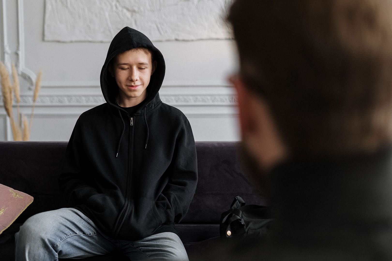 Teenager in a hoodie talking with a counsellor in a calm office