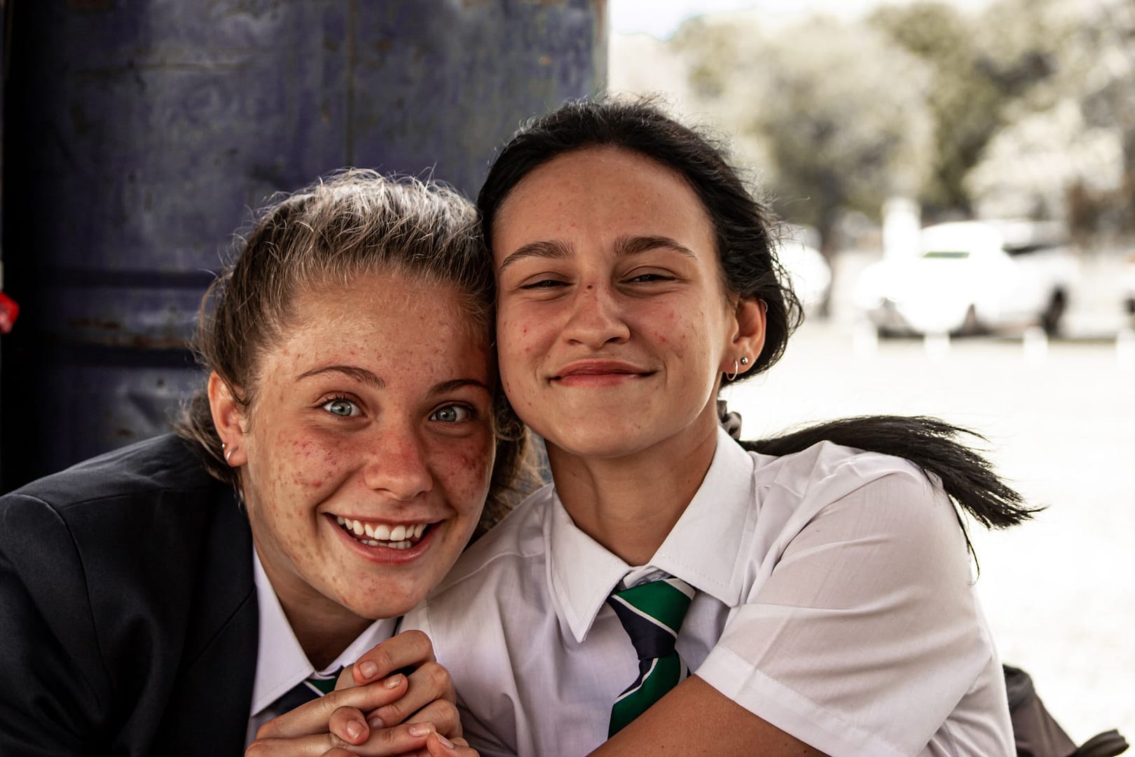 Two smiling teenagers in school uniform outdoors