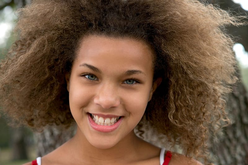 Smiling teenager with natural curls outdoors